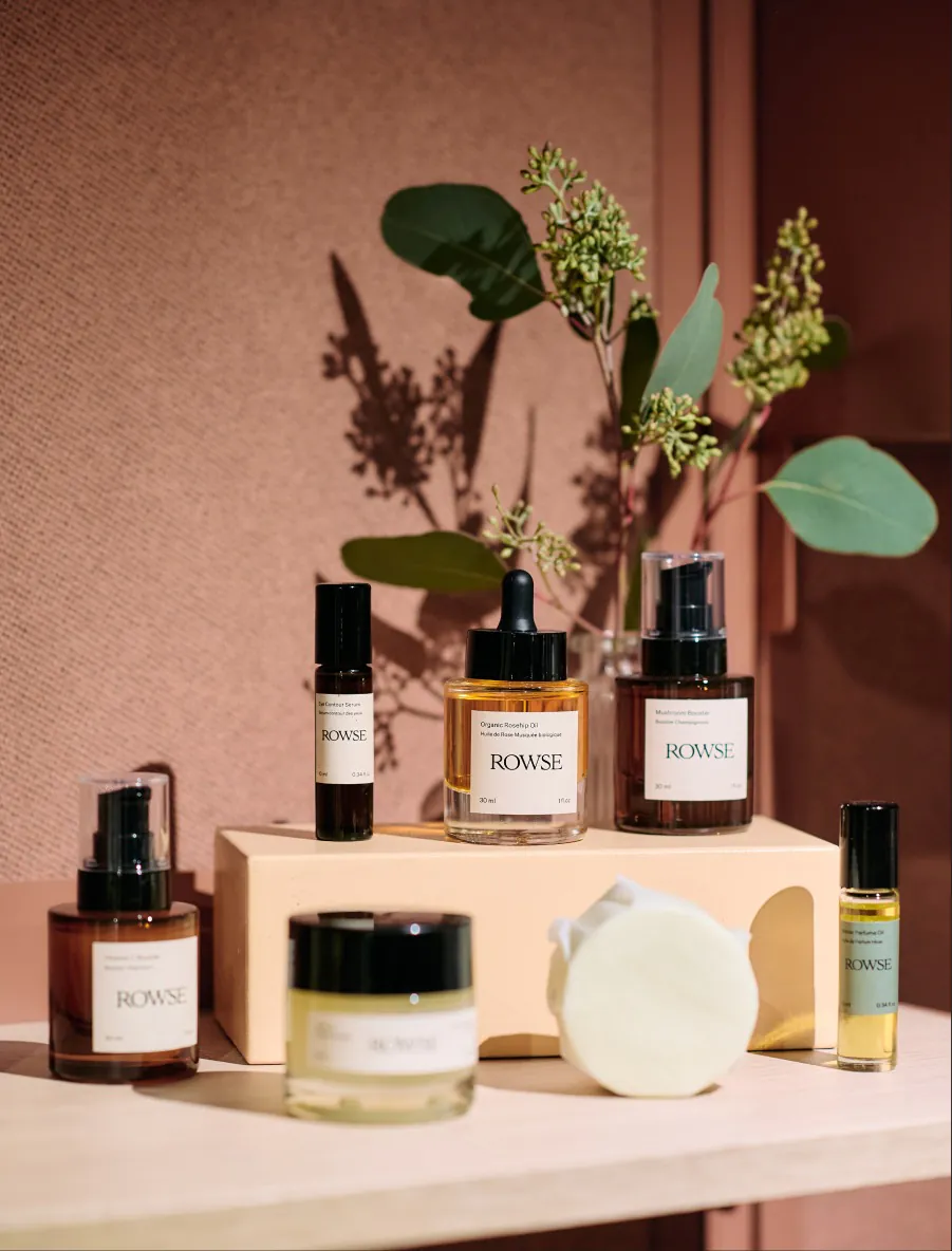 Skincare products on a peach shelf with eucalyptus shadows on the wall