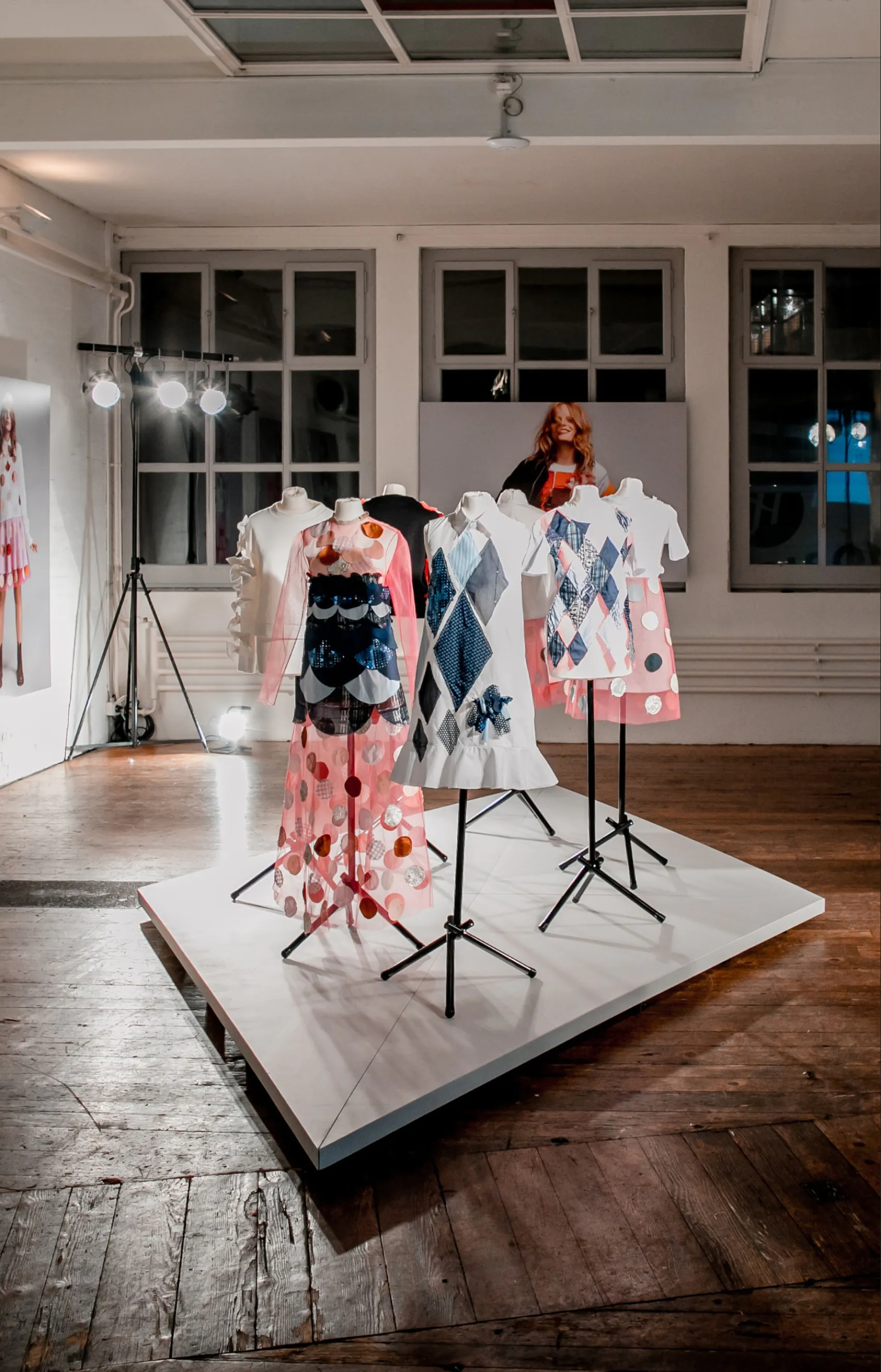 Dresses on mannequins on a white platform in a bright studio
